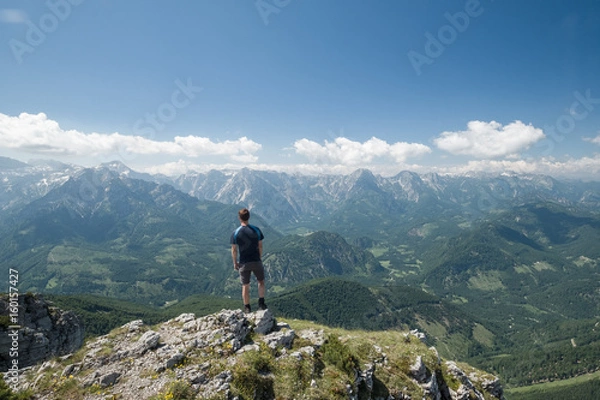 Fototapeta Man on top of a mountain looking at mountain range