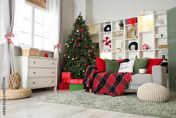 Fototapeta Interior of living room decorated for Christmas with sofa, shelving unit and dresser near window