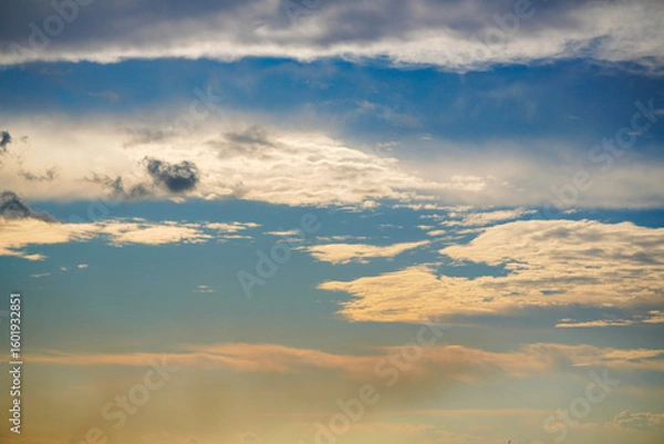 Fototapeta Beautiful evening sky with colorful orange and blue clouds reflecting on the water at dusk. Serene and peaceful nature background.