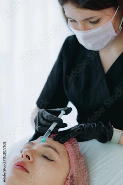 Fototapeta aesthetic professional performing an injection procedure in the glabellar region. Beauty treatment