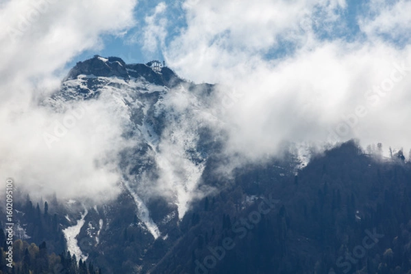 Fototapeta The mountain is covered in snow and the sky is cloudy