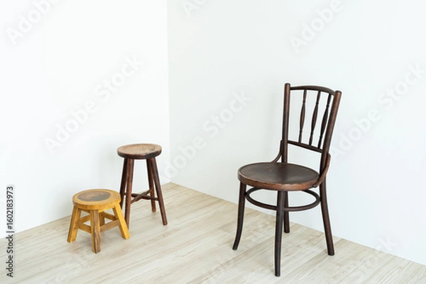 Fototapeta Wooden chairs of different sizes arranged in a white corner