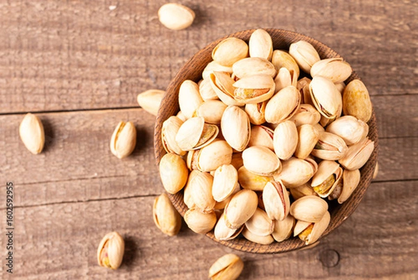 Fototapeta Organic roasted pistachio nuts in a wooden bowl. Top view. 