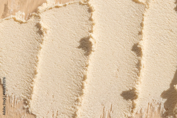 Fototapeta Smears of cosmetic exfoliating scrub on beige background, top view.