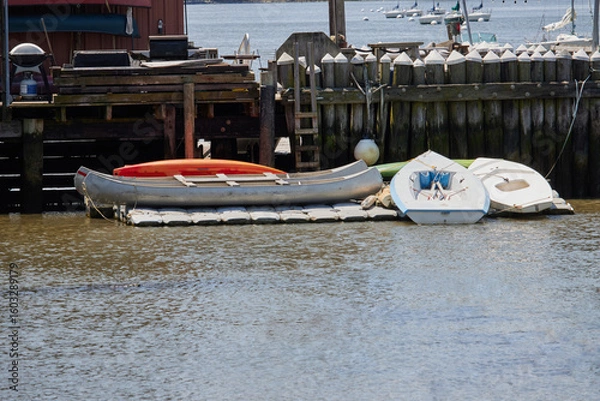 Fototapeta canoes and other small boats docked at a river pier on a bright sunny day in summer, copy space