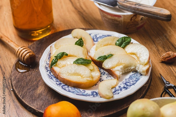 Fototapeta Bruschetta with ricotta and nectarines, garnished with honey and basil