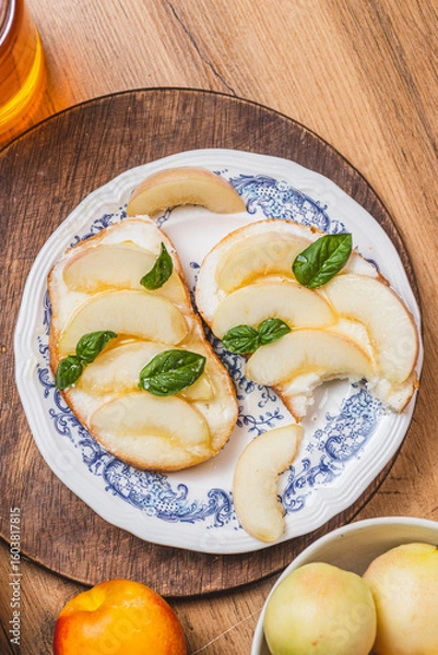 Fototapeta Bruschetta with ricotta and nectarines, garnished with honey and basil