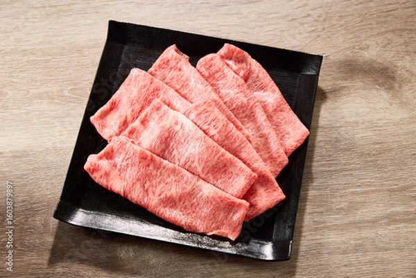 Obraz A5ランク黒毛和牛のローススライスを黒い角皿に美しく盛り付けた高級和牛のイメージ。霜降りのサシ模様が美しく、すき焼きやしゃぶしゃぶに最適な日本の高級食材。