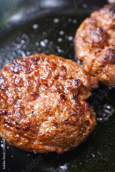 Fototapeta ハンバーグ - フライパンでハンバーグステーキを、ジュージュー音をさせながら焼く
