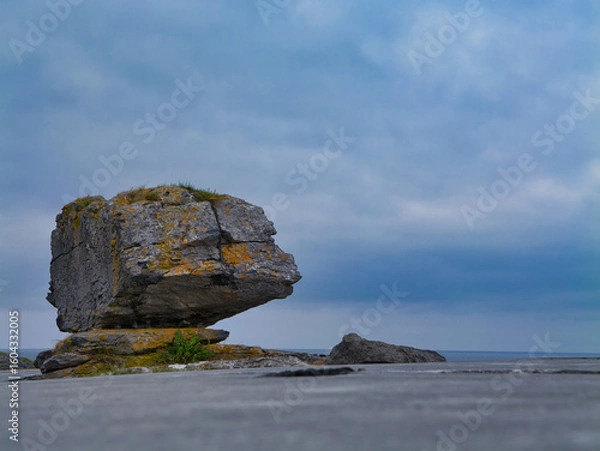 Fototapeta A striking erratic stands on the rugged limestone pavement of the Burren, Ireland, under a moody sky.