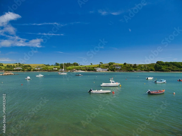 Fototapeta Scenic view of boats floating in the peaceful harbor of Castletownshend, Ireland, under a vibrant blue sky.