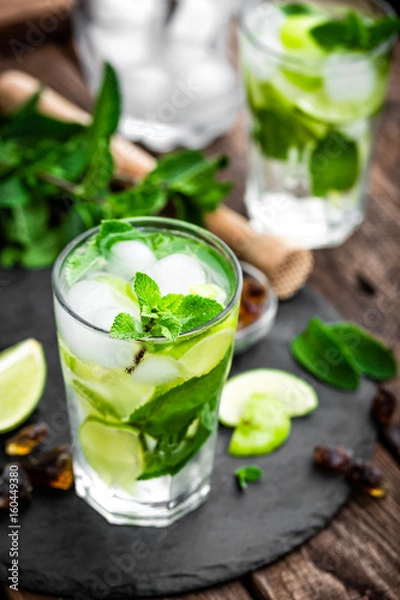 Fototapeta Refreshing mint cocktail mojito with rum and lime, cold drink or beverage with ice on black background