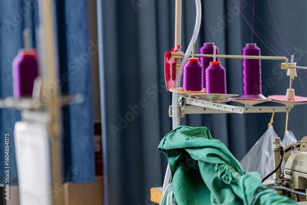 Fototapeta Gros plan sur des fils à coudre disposés sur un présentoir dans un atelier de couture, illustrant l’organisation et la diversité des matériaux.