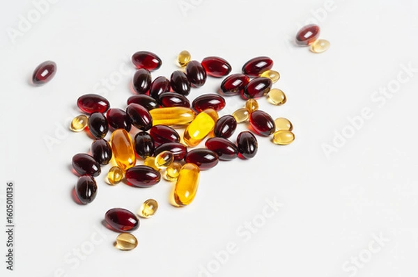 Fototapeta A close-up of various red and yellow capsules scattered on a white surface.