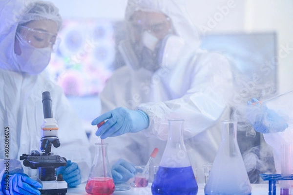 Obraz A team of chemists in hazmat suits discusses a breakthrough during a critical experiment in a secure lab. Concept for drug discovery and chemical research.