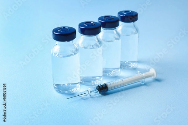 Fototapeta Vaccine in vials with syringe on color background