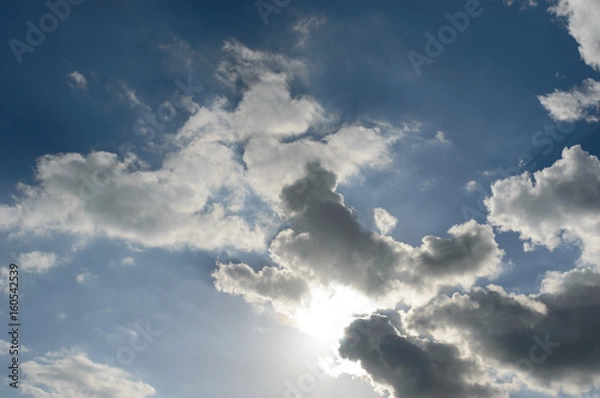Obraz Sun light breaking through dark storm cloud formations taking a bleu sky