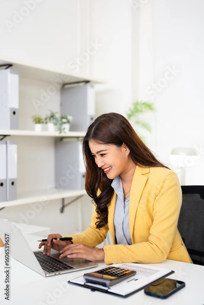 Fototapeta  Happy asian business woman using laptop computer typing And working sitting at desk in modern office wearing suits. Office worker lady browsing internet on computer. Entrepreneurship.