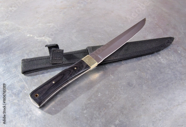 Fototapeta Hunting knife with a hard textile sheath, with a wide single-edged sharpened blade, on an isolated background.