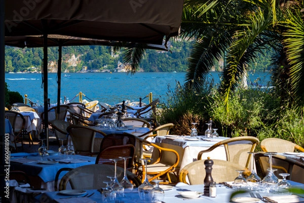 Obraz Cernobbio, Lake Como, Lombardy - July 7, 2025: View of Lake Como from a restaurant in Cernobbio. Tables are set ready to welcome tourists.