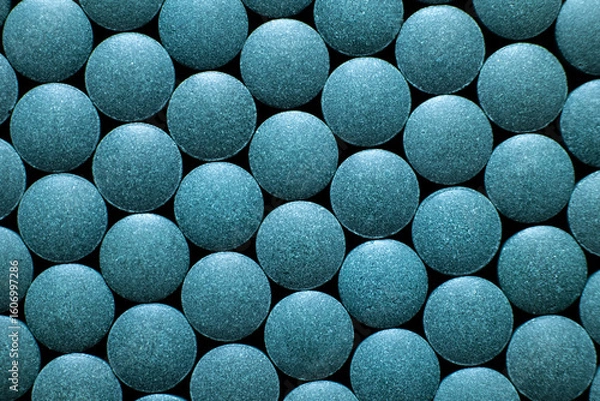 Fototapeta Multiple blue round tablets arranged in geometric pattern. Dietary supplement and pharmaceutical medicine concept. Macro shot photography.