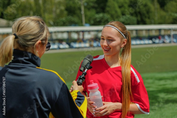 Fototapeta Woman footballer being interviewed on field after match. Concept of media in youth sports, athlete interaction with interviewer, sports journalism and youth campaigns.