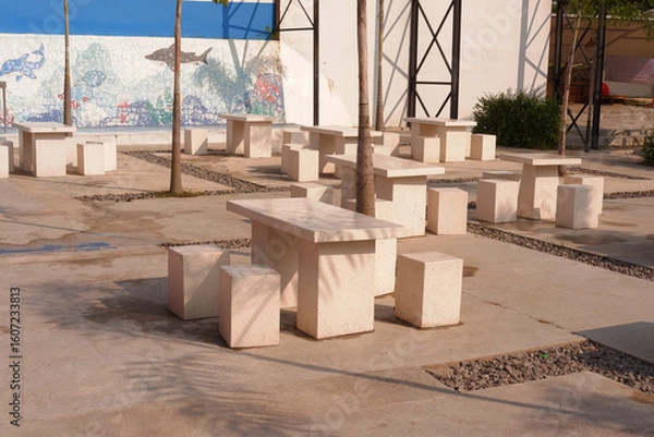 Obraz Outdoor cafe or coffee shop with a table and chairs set made of white natural stone. Modern interior design concept and furniture.
