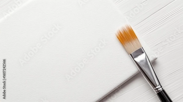 Fototapeta A pristine white canvas with a brush resting on it symbolizing a blank slate or fresh start