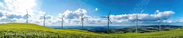 Fototapeta Wind turbines stand tall on a grassy hilltop under a vibrant blue sky dotted with fluffy clouds