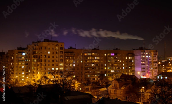 Obraz Photo of buildings at night with factory smoke above them