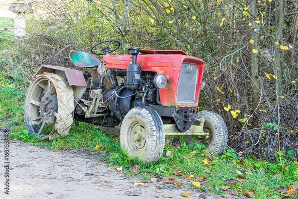 Fototapeta an old red farm tractor against the background of the forest