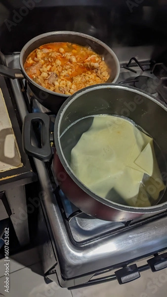 Obraz Lasagna pasta sheet, boiling water, and heating red pozole. Preparing lasagna for Christmas dinner.