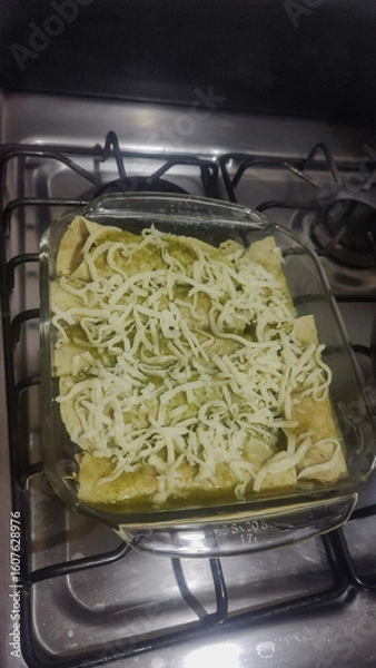 Obraz Vertical photo of delicious green chicken enchiladas with cheese.
