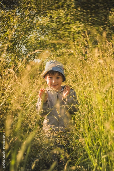 Fototapeta Smiling boy, making his way through the big grass
