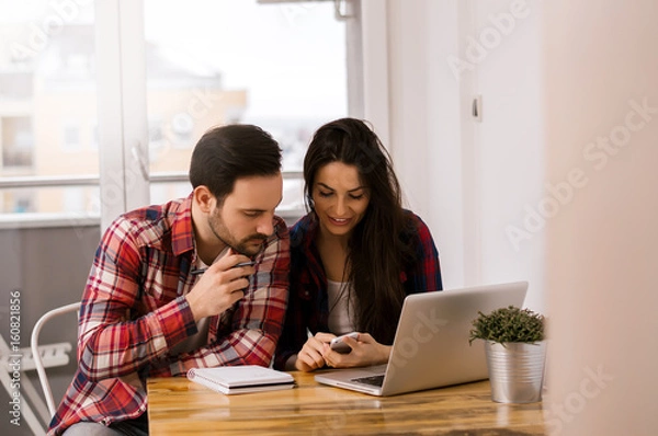 Fototapeta Two young students working on ther project at home
