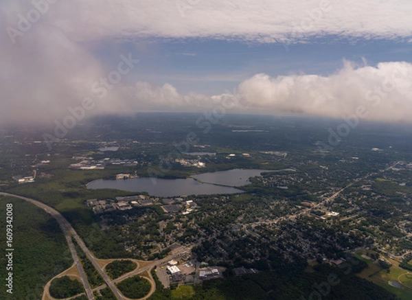 Fototapeta Aerial view of a town with lake and cloudy sky.