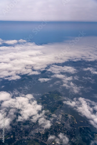 Fototapeta Aerial view of land, water, and clouds.