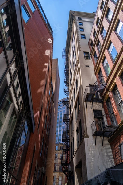 Fototapeta Looking up at buildings with fire escapes in Boston.