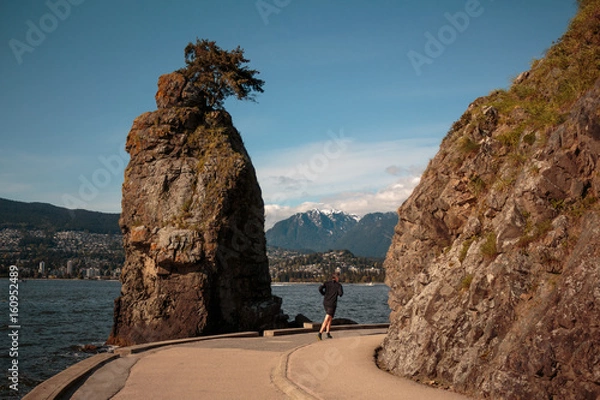 Fototapeta Photo of runner passing through Siwash rock at Stanley Park, Vancouver, BC