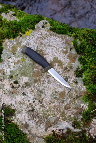 Obraz camping knife on a stone near a river