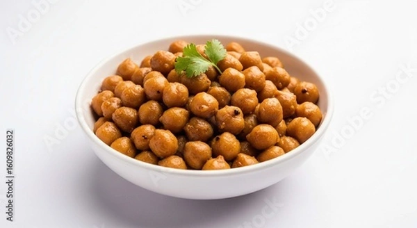 Obraz A white bowl filled with golden brown roasted chickpeas, garnished with a fresh green cilantro sprig, presented against a clean white background.