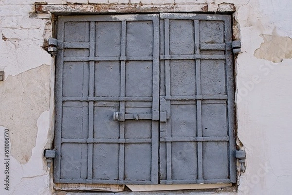 Obraz Vintage blue metal window shutters on a vibrant gray textured wall, with graffiti at the bottom.
