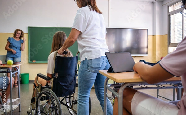 Fototapeta Teacher assisting a student in a wheelchair during inclusive classroom activity with tablets and diverse participation