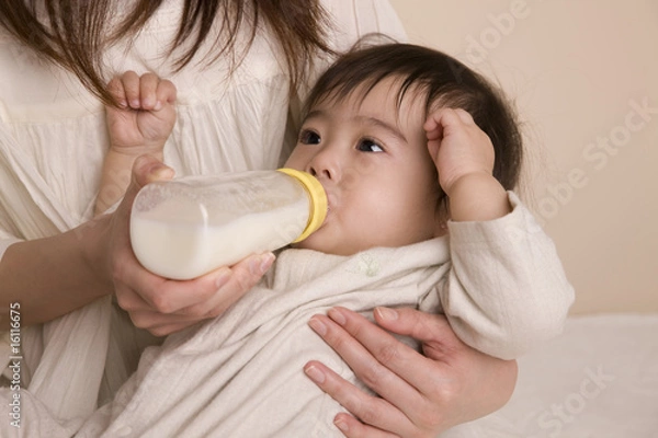 Fototapeta 母親に抱かれてミルクを飲む赤ちゃん