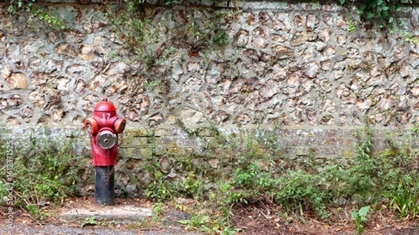 Obraz French fire hydrant in front of a stone wall in Normandy, France. Red and iconic.