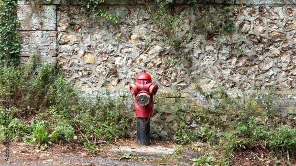 Obraz French fire hydrant in front of a stone wall in Normandy, France. Red and iconic.