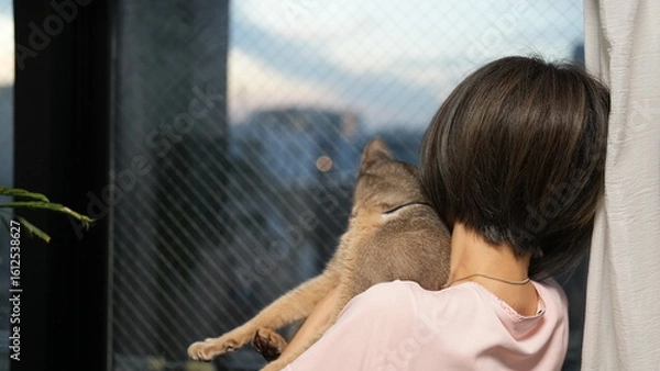 Obraz 猫をだっこして外を見つめる女性