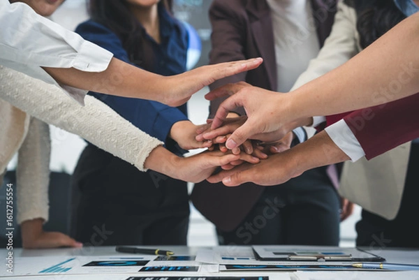 Fototapeta Business people joining hands together over meeting table after successful agreement showing teamwork, unity, cooperation, collaboration and support in business partnership