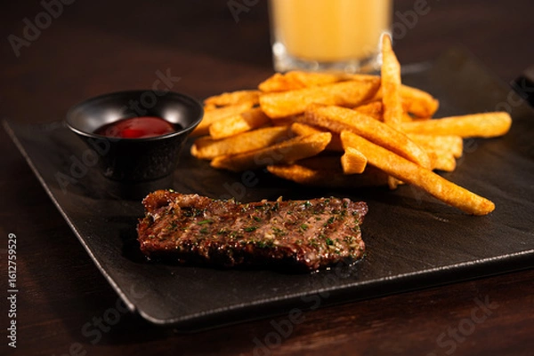 Obraz Grilled Beef Steak with French Fries and Ketchup on Black Plate