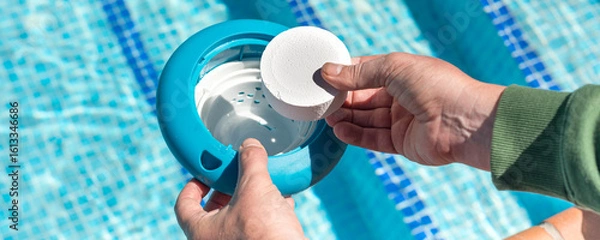 Obraz Hand placing chlorine tablet in floating pool dispenser